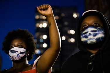 A demonstrator raises a fist during a "Sit Out the Curfew" protest against the death of George Floyd who died on May 25 in Minneapolis whilst in police custody, along a street in Oakland, California on June 3, 2020. - US protesters welcomed new charges against Minneapolis officers in the killing of African-American man George Floyd -- but thousands still marched in cities across the country for a ninth straight night, chanting against racism and police brutality.