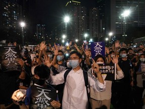 People gesture the popular protest slogan 'Five demands, not one less' as they attend a vigil in Victoria Park in Hong Kong on June 4, 2020, after the annual remembrance that traditionally takes place in the park to mark the 1989 Tiananmen Square crackdown was banned on public health grounds because of the COVID-19 coronavirus pandemic.