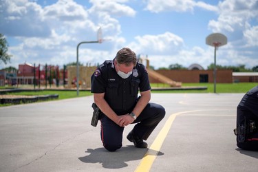 TOPSHOT - A police officer takes a knee during a 9 minute moment of silence in honor of George Floyd during a "Sit In Protest" to mourn the death of George Floyd at DeepWater Park in Pasadena, Texas on June 7, 2020. - On May 25, 2020, Floyd, a 46-year-old black man suspected of passing a counterfeit $20 bill, died in Minneapolis after Derek Chauvin, a white police officer, pressed his knee to Floyd's neck for almost nine minutes.