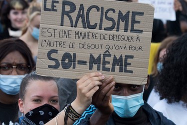 People hold a placard reading "Racism is a way of delegating to someone else its own self-disgust" as they demonstrate in Nantes, on June 8, 2020, during a 'Black Lives Matter' worldwide protests against racism and police brutality in the wake of the death of George Floyd, an unarmed black man killed while apprehended by police in Minneapolis.