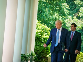 In this file photo taken on May 15, 2020, U.S. President Donald Trump walks with Defense Secretary Mark Esper through the Colonnades on his way to speak on vaccine development in the Rose Garden of the White House in Washington, D.C.
