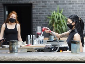 Bartender Alicia Mattoe, right, makes a drink as patrons sit on the patio at Joey Sherway, part of the Joey Restaurant chain during the COVID-19 pandemic in Toronto on Wednesday, June 24, 2020. Toronto and the GTA entered stage two of opening. /Nathan Denette ORG XMIT: NSD110