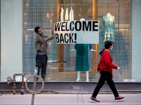 An employee at Zara puts up a sign during a phased reopening from COVID-19 restrictions in Toronto, May 19, 2020.