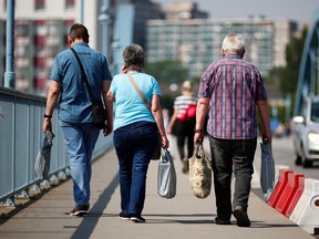 People cross a city bridge in Frankfurt, Germany on June 13, 2020.