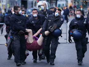 BERLIN, GERMANY - MAY 01: Police arrest a demonstrator who took part in a protest against government lockdown measures on May Day during the novel coronavirus crisis on May 1, 2020 in Berlin, Germany. May Day protests are taking place across Germany today, though as gatherings are limited by authorities to a maximum of 20 people per gathering due to coronavirus lockdown measures, many small protests are taking place instead of traditional, large-scale marches. (Photo by Sean Gallup/Getty Images)