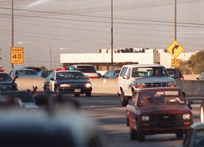 Motorists wave as police cars pursue the Ford Bronco driven by Al Cowlings, carrying fugitive murder suspect O.J. Simpson, on a 90-minute slow-speed car chase June 17, 1994 on the 405 freeway in Los Angeles. Simpson’s friend Cowlings eventually drove Simpson home, with Simpson ducked under the back passenger seat, to Brentwood where he surrendered after a stand-off with police. GETTY IMAGES FILE