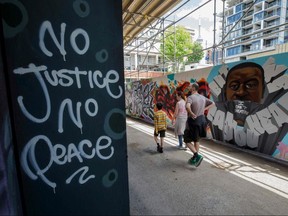 People walk by a mural of George Floyd in Graffiti Alley in Toronto June 11, 2020.