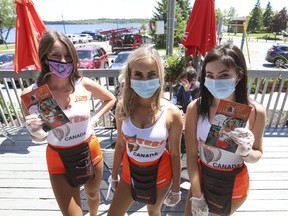 Hooters Barrie staff from left: Sam, Lacey and Reigan hold up disposable menus on the lower patio. They were happy that businesses have been able to open again -- well, at least their two patios with social distancing in affect on Friday, June 12, 2020.