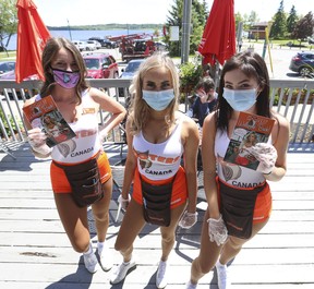 Hooters Barrie staff from left: Sam, Lacey and Reigan hold up disposable menus on the lower patio. They were happy that businesses have been able to open again -- well, at least their two patios with social distancing in affect on Friday, June 12, 2020.
