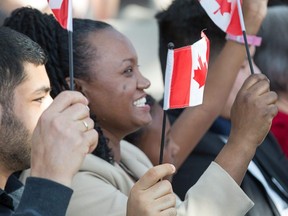 Amarech Yemane Habtemariam (centre) waves her flag as the Institute for Canadian Citizenship, together with Immigration, Refugees and Citizenship Canada, and the National Gallery of Canada, held a special community citizenship ceremony in the Great Hall at the National Gallery of Canada. Photo by Wayne Cuddington/ Postmedia