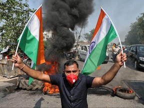 A demonstrator holds Indian flags in front of burning tires during a protest against China, in Jammu, June 17, 2020.