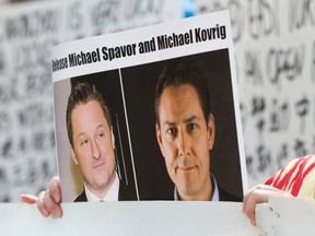 In this file photo taken May 8, 2019, Turnisa Matsedik-Qira, of the Vancouver Uyghur Association, demonstrates against China's treatment of Uighurs while holding a photo of detained Canadians Michael Spavor (left) and Michael Kovrig (right) outside a court appearance for Huawei Chief Financial Officer, Meng Wanzhou, at the British Columbia Supreme Court in Vancouver.