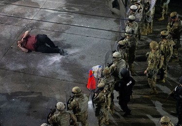 A man lies on the ground grasping a cane after law enforcement deployed chemical agents and blast balls to disperse a protest against racial inequality in the aftermath of the death in Minneapolis police custody of George Floyd, near the Seattle Police department's East Precinct in Seattle, Washington, U.S. June 8, 2020.