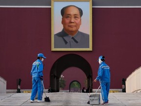 Two cleaners clean the ground in front of the portrait of the late Communist Party leader Mao Zedong on April 29, 2020 in Beijing, China.