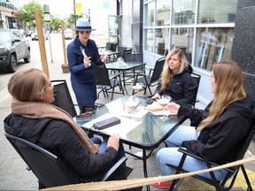 Server Emma McDaniel, middle, of The Cedar Nest in Sudbury, Ont., serves customers Tori Frame, left, Connor Lacroix and Taylor Noel in the patio area of the restaurant on Friday June 12, 2020.