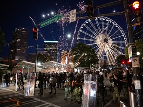 A firework thrown by protesters goes off amid police in riot gear during a protest in Minneapolis. One company is leaving the area after ensuing riots burned down its factory.