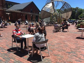 People gather at tables in the common area of Toronto's Distillery District on Saturday, June 13, 2020.