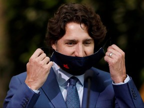 Prime Minister Justin Trudeau removes his mask before making a commencement speech during a ceremony with post-secondary graduates in Ottawa June 10, 2020.