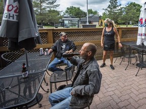Bartender Shannon Tonkin, chats with their first customers - Hugh Skip MacDougall (front) and Paul Holwell, on the first day of the open patio at Mulligan's Pub in Mississauga, Ont. on Wednesday June 24, 2020.