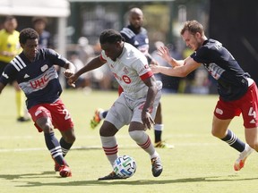 DeJuan Jones #24 and Henry Kessler #4 of New England Revolution defend Ayo Akinola #20 of Toronto FC during a Group C match as part of the MLS Is Back Tournament at ESPN Wide World of Sports Complex on July 21, 2020 in Reunion, Florida.