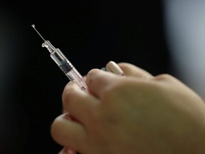 In this file photo, a nurse prepares a flu vaccine