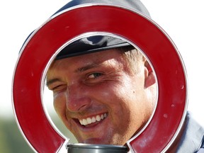 Bryson DeChambeau looks through the trophy after winning the Rocket Mortgage Classic at Detroit Golf Club yesterday.