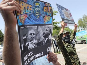 A protester holds a placard bearing the images of George Floyd, Malcom X and Martin Luther King on June 8, 2020, in Ankara, during a demonstration against racism and police brutality, and in solidarity with the Black Lives Matter movement, in the wake of the death of George Floyd, an unarmed black man killed while apprehended by police in Minneapolis, US.