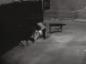 A man lights a fire in an alley at Queen and Shaw Sts. on July 5, 2020.