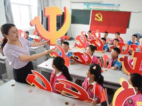 In this file photo a teacher and her students pose with Communist Party emblems during a class about the history of the Communist Party at a school in Lianyungang, on June 28, 2020.
