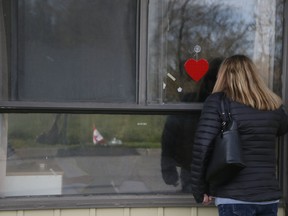 Diane Colangelo, daughter, looks through the window as Patricia Crump, 86,  lies on a bed inside Pickering's Orchard Villa long-term care home on Tuesday May 5, 2020.