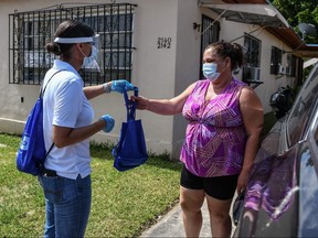 Catherimarty Burgos, a member of Miami-Dade County "surge teams" distributes bags with masks, sanitizers, and gloves to educate people on how to stay safe from COVID-19, in Miami on April 30, 2020.