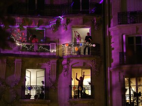 People dance on the balcony of their apartments while music is played by two DJs during a two-hour party on April 24, 2020 in Paris, as the country is under lockdown to stop the spread of the COVID-19 pandemic.
