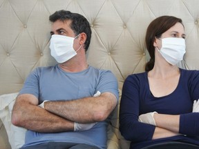 An upsets couple in isolation wear face masks and protective gloves.