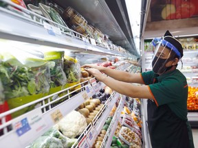 A worker wearing a face shield and a protective face mask checks the vegetables amid the outbreak of the coronavirus.
