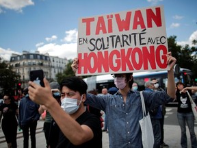 A man wearing a protective mask holds a placard reading "Taiwan in solidarity with Hong Kong" as he demonstrates in support of Hong Kong protesters opposed to China's national security law and to urge French authorities to take a stronger stand against Chinese policy, in Paris, July 11, 2020.