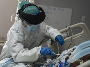 A member of the medical staff wearing full PPE brushes a patient's teeth in the COVID-19 intensive care unit at the United Memorial Medical Center in Houston, June 30, 2020.