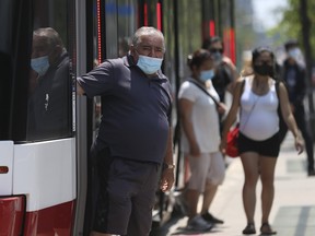 Riders leave a TTC streetcar on Spadina Ave., at Queen St. W. in Toronto on Thursday, July 2, 2020.