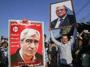 Protesters hold posters of imprisoned leader of the Popular Front for the Liberation of Palestine (PFLP) Ahmed Saadat (left) and Palestinian President Mahmud Abbas during a demonstration against Israel's West Bank annexation plans, in Khan Yunis in the southern Gaza Strip, July 2, 2020.