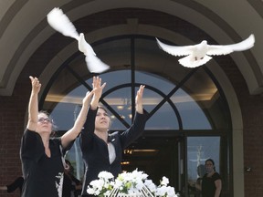 Josée Masson, left, and Marie-Eve Garneau release two doves at end of the funerals of Romy and Norah Carpentier in Lévis on Monday.