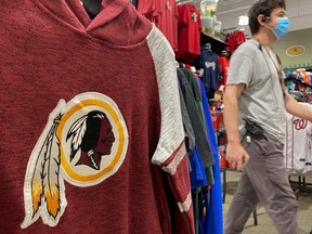 An employee passes a Washington Redskins shirt for sale at a sporting goods store in Bailey's Crossroads, Virginia, June 24, 2020.
