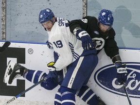 Jason Spezza takes Jake Muzzin into the boards as the Maple Leafs opened camp in Toronto on Monday.