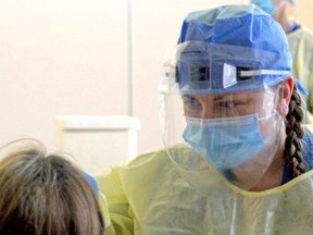 A worker in Ontario performs a COVID-19 test on a citizen in June.