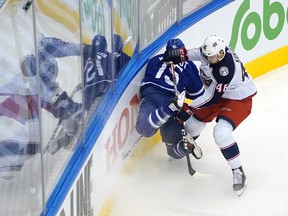 Alexander Kerfoot of the Maple Leafs is hit by Dean Kukan of the Columbus Blue Jackets in Game 1 last night in Toronto.