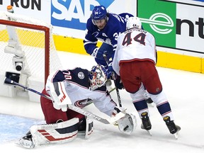 Joonas Korpisalo  of the Columbus Blue Jackets stops a shot as Leafs' Auston Matthews is kept out of harm's way by defenceman Vladislav Gavrikov during the second period of Game 1 last night at Scotiabank Arena.