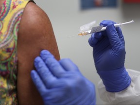 A woman receives a COVID-19 vaccination from a nurse as she takes part in a vaccine study at Research Centers of America on Aug. 7, 2020 in Hollywood, Florida.