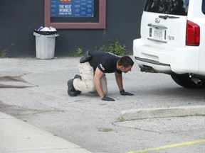 A York Regional Police officer looks under a vehicle while investigating a murder in Woodbride on Aug. 3, 2020.