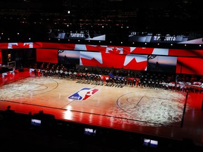 Players take a knee during the Canadian national anthem before the start of yesterday's game between the Raptors and Nets.