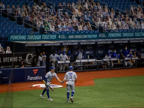 Toronto Blue Jays second baseman Brandon Drury, right, walks to the dugout after scoring during the second inning of a game against the Tampa Bay Rays at Tropicana Field in St. Petersburg, Fla., Aug. 21, 2020.