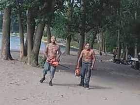 Two men wield chainsaws at Cherry Beach.