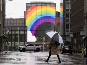 A large rainbow is shown on the National Arts Centre as a woman walks across a quiet street in downtown Ottawa, Tuesday, April 21, 2020 in Ottawa.